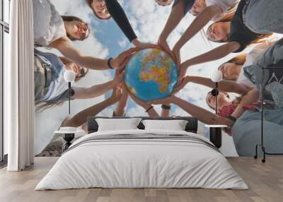 Earth conservation concept. 11 girls hug the earth globe with their hands. Wall mural