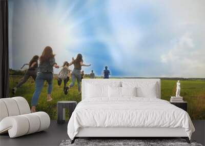 Happy friends run against the backdrop of a beautiful sky and sun. Wall mural