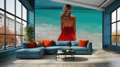 A woman in a bright red dress stands alone on the beach, with the ocean and sky as her backdrop Wall mural