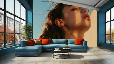 A woman relaxing outside, hair blowing in the breeze Wall mural