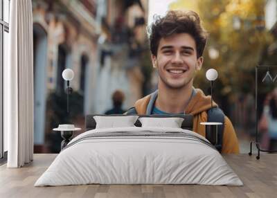 A young man with a backpack smiles at the camera. Suitable for travel and lifestyle concepts Wall mural