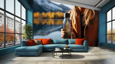 Girl holding water bottle against background of lake with mountains Wall mural