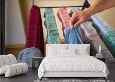 A man is hanging laundry indoors beside a sunlit window, an engaging domestic activity Wall mural