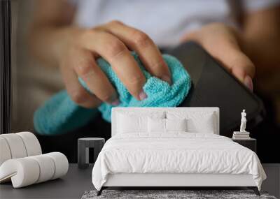 A person is using a microfiber cloth to clean their smartphone for hygiene purposes Wall mural