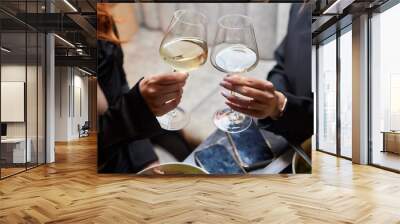 A woman holds a cocktail in her hand, with her fingers wrapped around the glass Wall mural