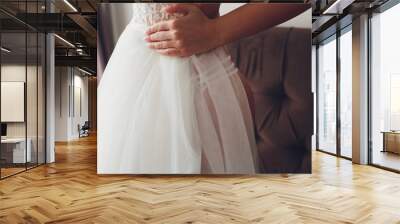 Closeup toned photo of beautiful bride tying up her wedding dress. Wall mural