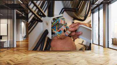 Electrician fixing complex wiring in junction boxes, showing expertise in electrical systems Wall mural