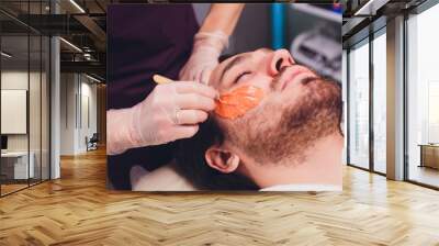 Hair removal. Man's face sugaring epilations beard trimming, yellow color, in cosmetology on the couch. Wall mural