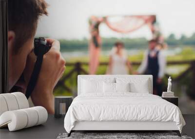 wedding photographer takes pictures of bride and groom in city. wedding couple on photo shoot. photographer in action. Wall mural