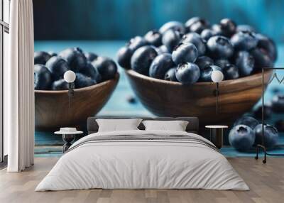 Two bowls of blueberries on a wooden table. The bowls are full of blueberries and there are many of them on the table Wall mural