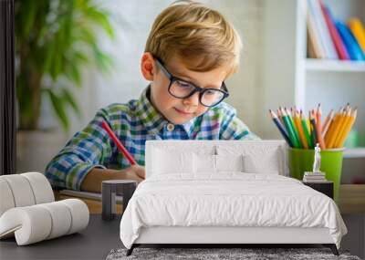 A young boy is sitting at a desk with a pencil and a piece of paper Wall mural