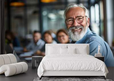 Senior businessman smiling during a meeting in the office. A warm smile lights up the room as the senior businessman leads the discussion. Wall mural