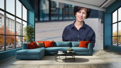 Happy positive mature adult businesswoman standing outdoors business centre smiling, looking at camera. Portrait of middle aged brunette woman, beautiful lady with copy space. Attractive female posing Wall mural