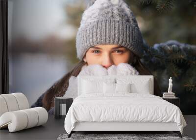 Portrait of beautiful girl young frozen pretty woman standing walking in winter snowy park at cold snow frosty day in hat, scarf, in gloves looking at camera Wall mural