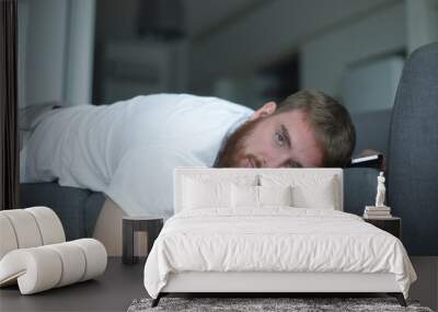 Young bearded man sleep at home on couch with his cell mobile phone in living room. Smartphone addiction concept.  Wall mural