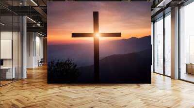 silhouette of a wooden cross stands prominently against a breathtaking sunset backdrop on a mountain. The dramatic interplay of light and shadow highlights the cross, creating a serene and sacred atmo Wall mural