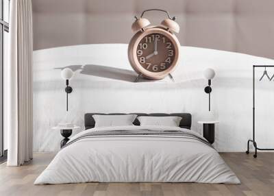 Alarm clock stands on pillow in morning sunlight, morning wake up time, sleep time, healthy sleep Wall mural