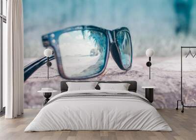 Fashionable sunglasses. Sunglasses with mirrored lenses. Reflection of the beach and tropical palm trees in sunglasses Wall mural