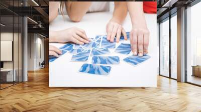 Cropped photo of group of children playing board game card game geistes blitz on table, touching blue card face down. Wall mural