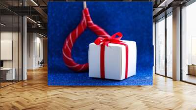 White gift box tied with a red ribbon on a blue background. Gift. Wall mural