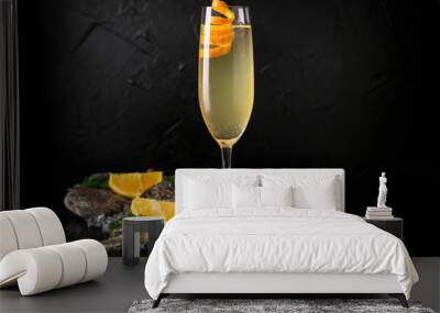 French 75 refreshing alcoholic beverage based on champagne, gin and sugar syrup on a black background with stones and ice. Cocktail card for a bar or restaurant. Wall mural