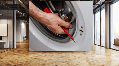 Handyman repairing a washing machine. The hands of man repair a washing machine. Wall mural