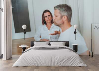 A man and a woman sitting in lotus position, the man wearing a blindfold while practicing breathing exercises with the woman's coaching Wall mural