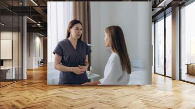 Consultation in cosmetology clinic. Female beauty doctor talking with patient.  Wall mural