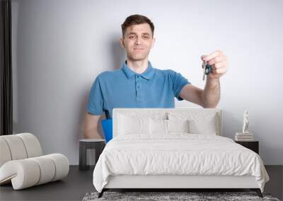 A man in a blue shirt holding a key and a blue folder Wall mural