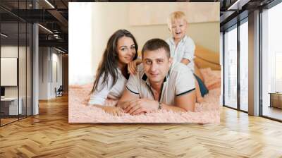 happy family lying on the bed and hugging, mom dad and little son Wall mural