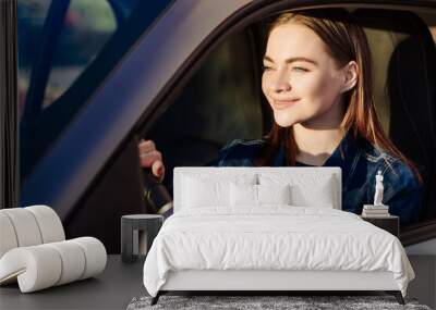 Nice young lady happy car. Image beautiful young woman who drives car and smiles. Portrait of a steering car with a driver of a happy woman with a seat belt Wall mural