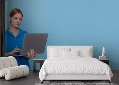 serious beautiful young woman in casual blue shirt dress posing standing, working on laptop, doing w Wall mural