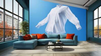 White shirt with ghost model floating in blue background. Snow-white shirt flies in the sky. Perfectly white clothes after washing, without human body. Bleach, laundry, dry. Mockup Wall mural