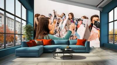 Young women paint with brushes on easels in art class. art school, creativity and people concept Wall mural