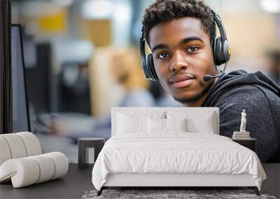 Wearing a headset and working at a computer, young man working in customer service. Wall mural