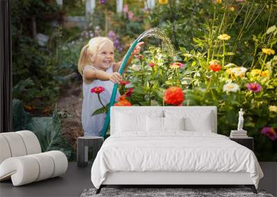 girl child in the garden watering plants, a small gardener, summer in the village Wall mural