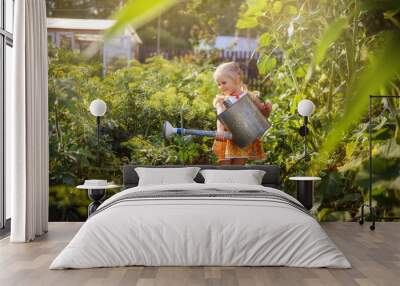 Girl watering the garden with a watering can, garden, little gardener, July, summer in the village, happy child Wall mural