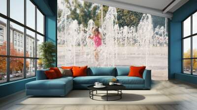 child playing with water in a dry fountain on the urban plaza Wall mural