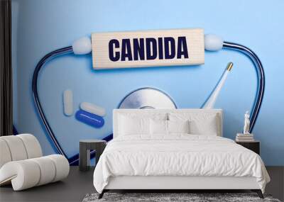 On a light gray background, a stethoscope, an electronic thermometer, pills, a wooden block with the text CANDIDA. Medical concept. Wall mural