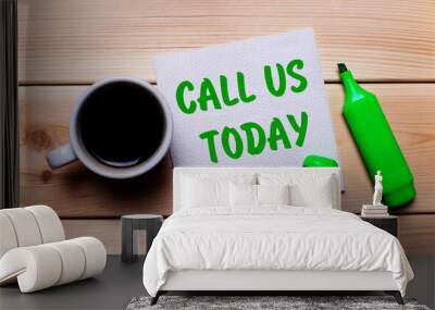 On a wooden table, a cup of coffee, a green marker and a napkin with the text CALL US TODAY Wall mural