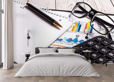 On a wooden table are color charts, a calculator, pen and glasses in black frames. Business format Wall mural