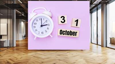 Two wooden cubes and a block with the text OCTOBER 31 and a white alarm clock on a light pink background. Wall mural