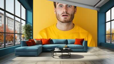 a young guy with a surprised face in yellow clothes on a decom background Wall mural