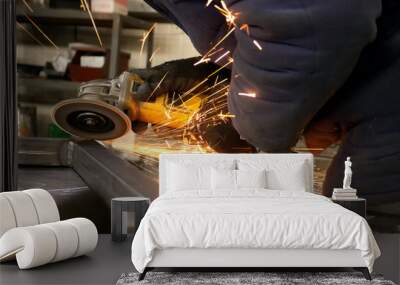 a man in special protective clothing, in the workshop for processing metal products with the help of a special device processes, grinds the metal surface after welding, the atmosphere is labor, Wall mural