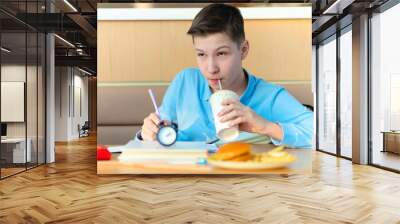 schoolchild doing homework, studing at school. boy waiting for lunch break at school. improper unhealthy diet of children. fast food kids Wall mural