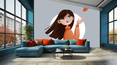 A white young girl in an orange sweater catches an autumn leaf with her hand Wall mural