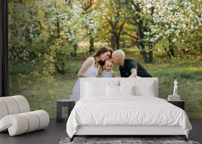 A happy young family with one small child walking having fun laughing spending time together in the park in nature on vacation in the summer outdoors, family day Wall mural