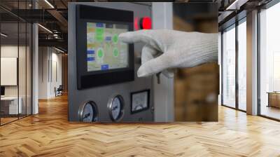 Worker hand in a white glove presses on the touch screen control panel equipment in the factory. Control machine operating parameters via touch screen. Worker hand at the workplace. Selective focus Wall mural