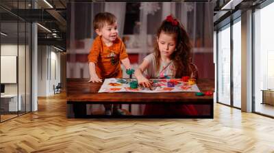 Cute little girl and boy painting with fingers at home. Creative games for kids. Stay at home entertainment Wall mural