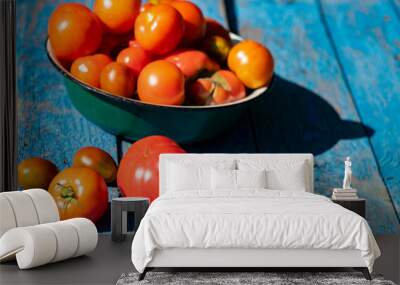 Organic tomatoes in metal enamel bowl on weathered blue wooden surface Wall mural